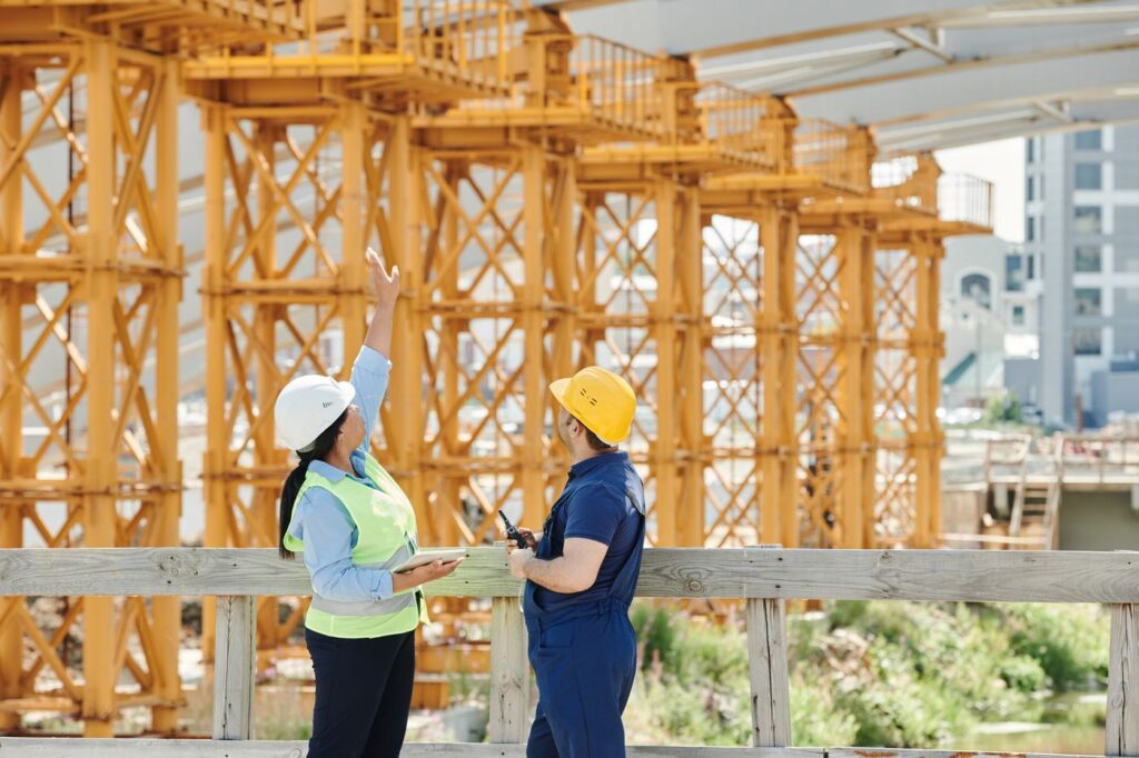 Supervisor and worker in safety gear talking at a construction site